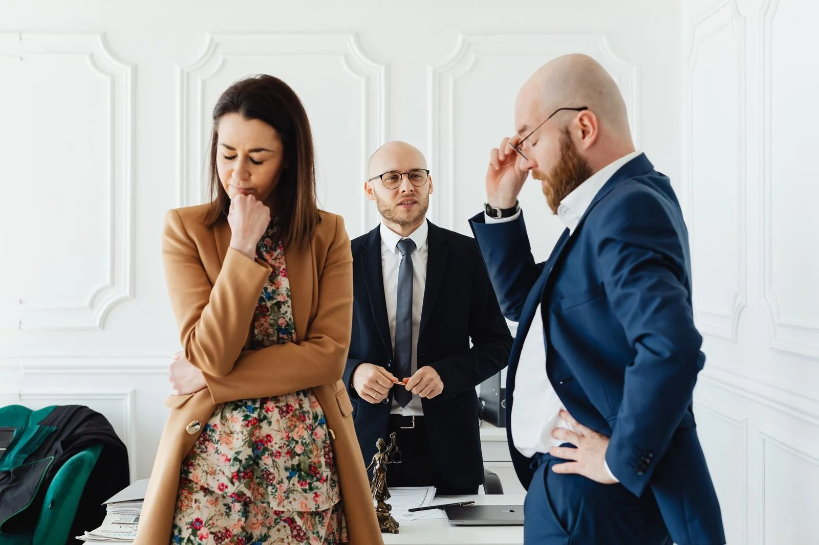 A couple seated across from a lawyer at a desk in a formal office.