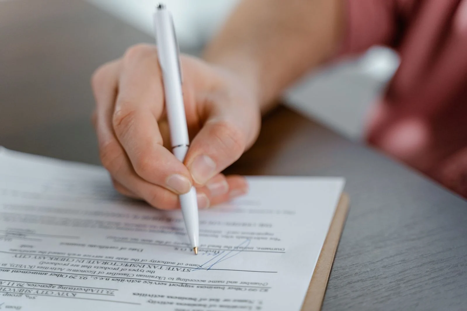 Una mano firma un documento oficial con un bolígrafo.