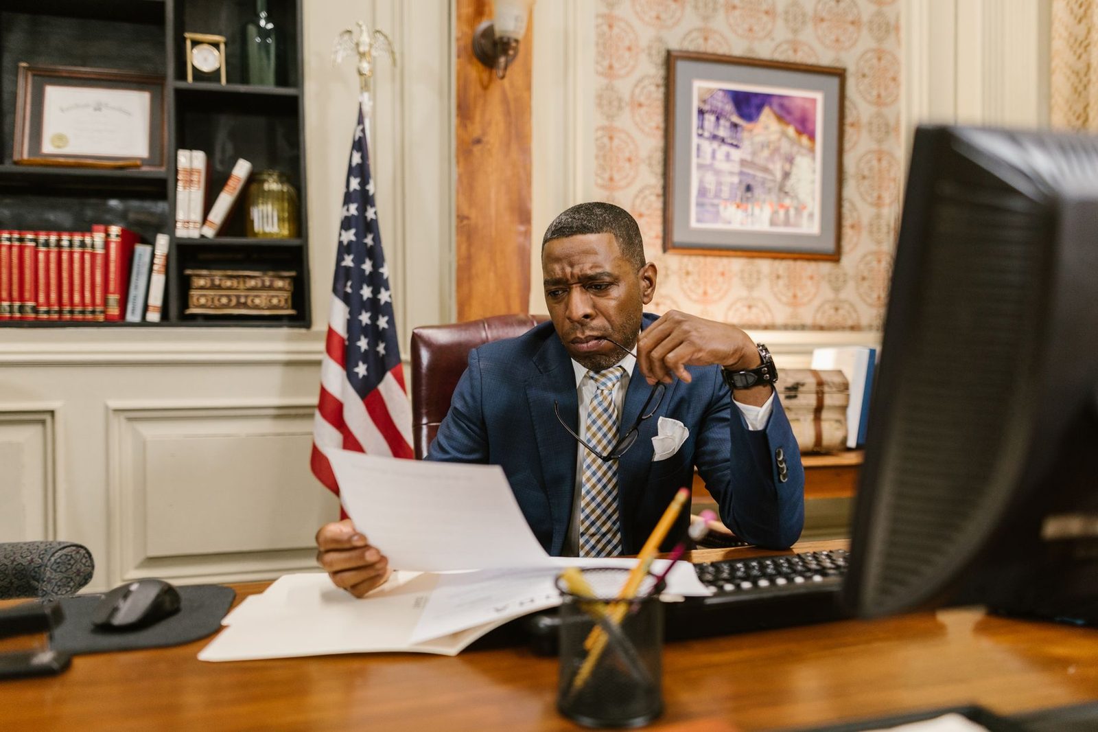 A lawyer in a professional office reviews legal documents at a desk.