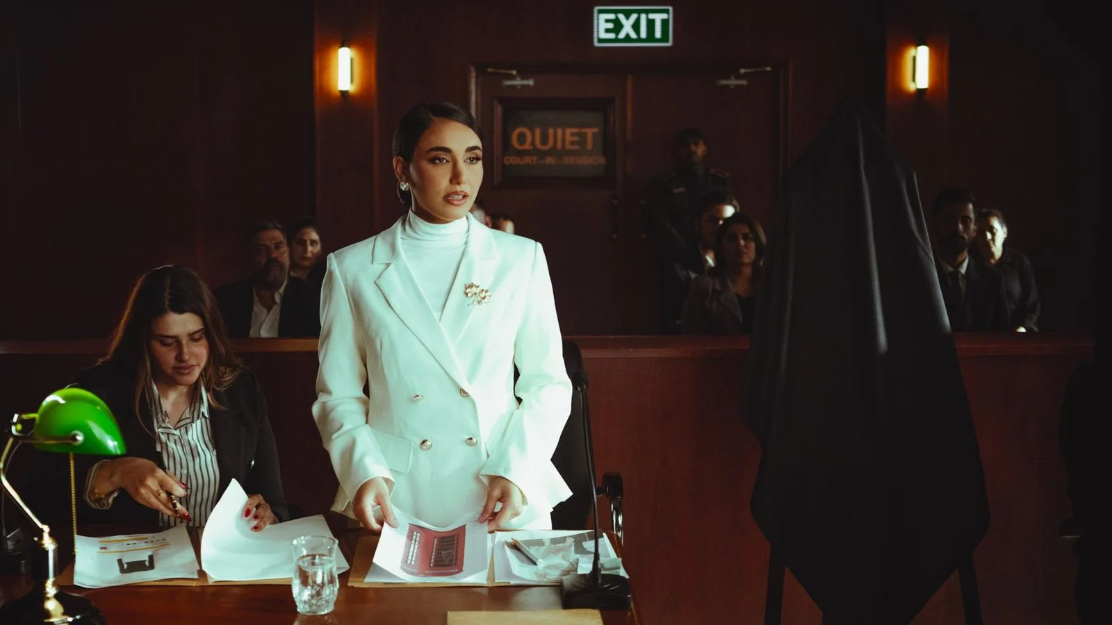 A lawyer in a white suit presents a case confidently during a courtroom session.