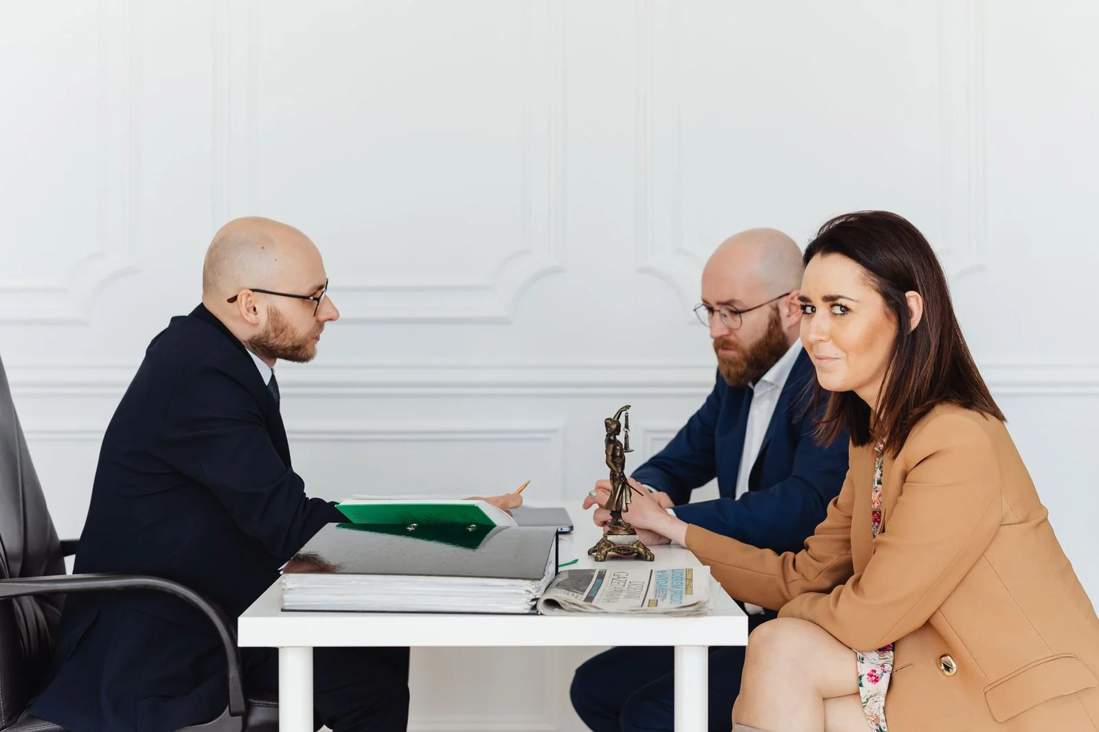 A lawyer meets with a couple across a desk in an elegant office, discussing legal documents.
