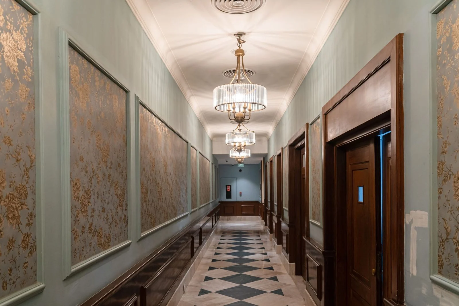 A luxurious hallway with chandeliers and ornate wall panels.