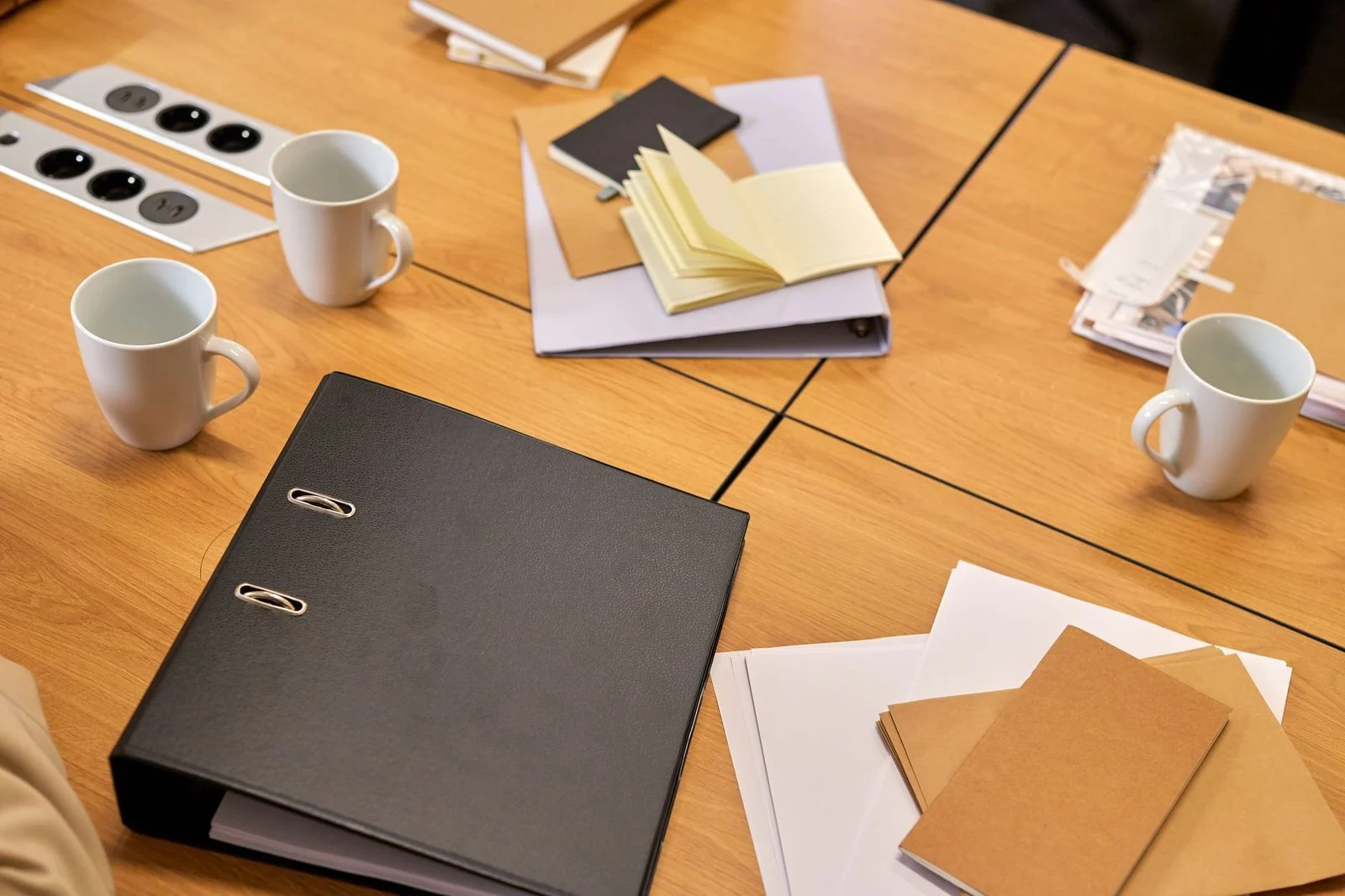 A neat office desk with binders, papers, and coffee mugs arranged in a professional workspace.