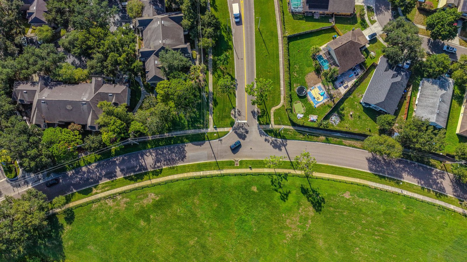 Aerial view of a Florida suburban neighborhood with rows of homes, winding roads, and green trees.