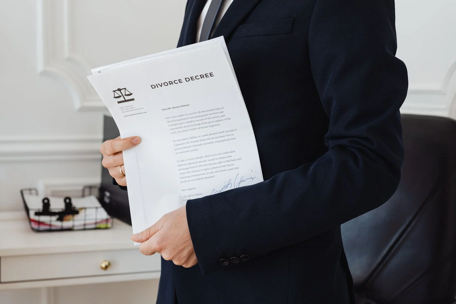 A person in an office holds a document while seated at a desk with legal papers.