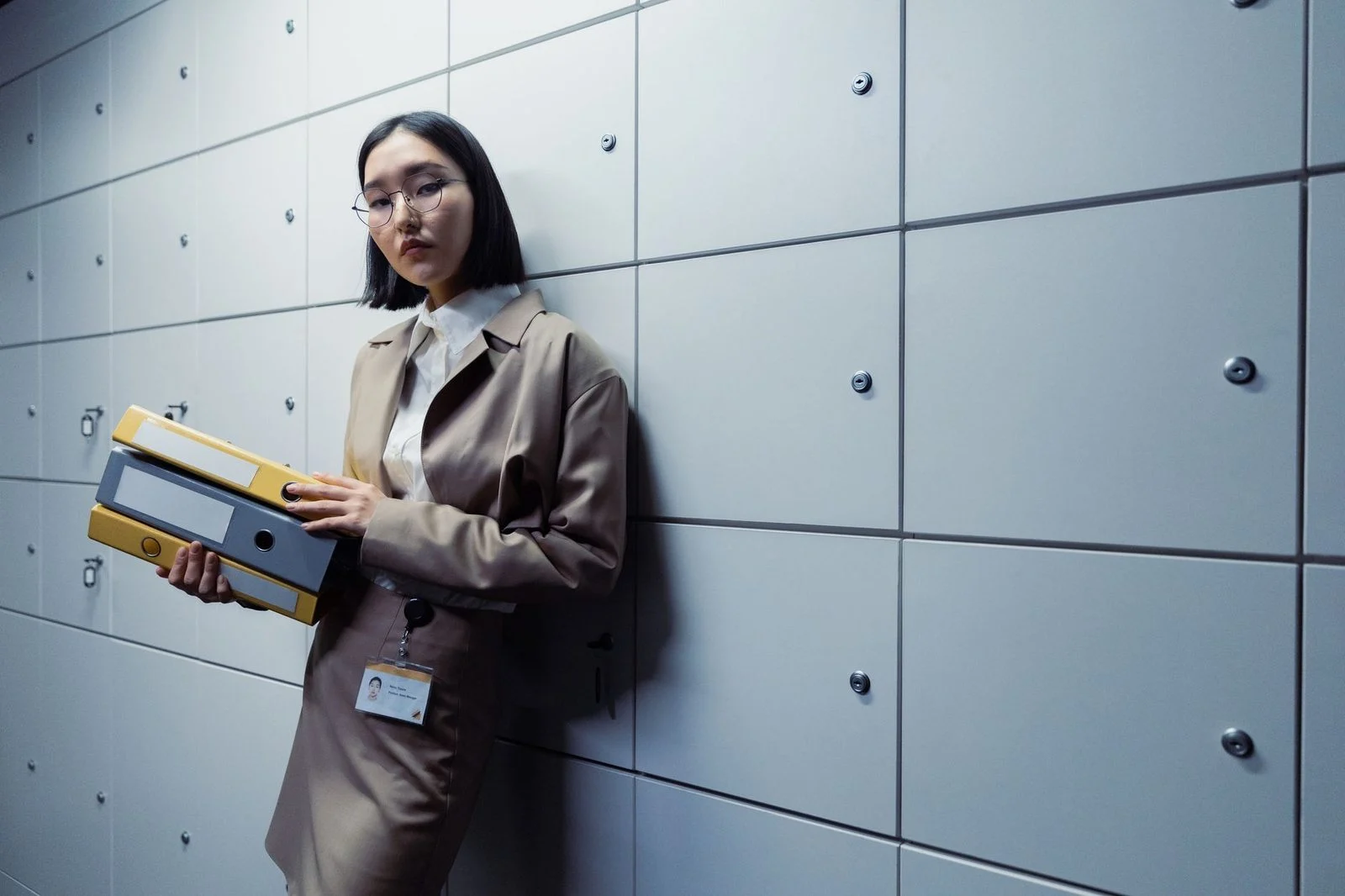 Businesswoman in professional attire holds documents while standing confidently in a modern office.