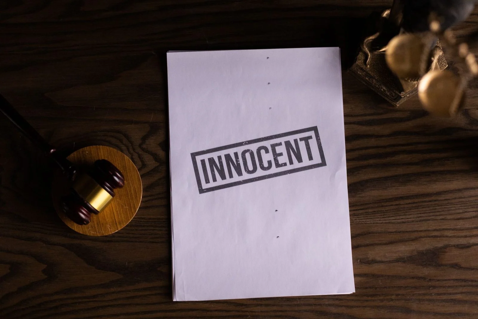 Close-up of a legal document stamped "Innocent" beside a gavel on a wooden desk.
