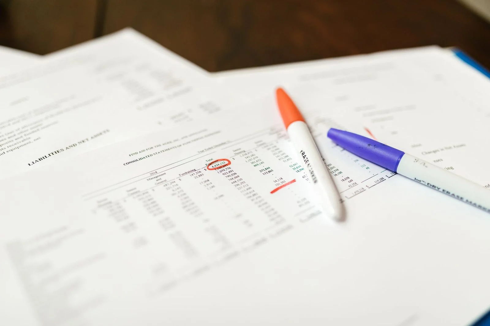 Close-up of financial documents with pens highlighting key data points.