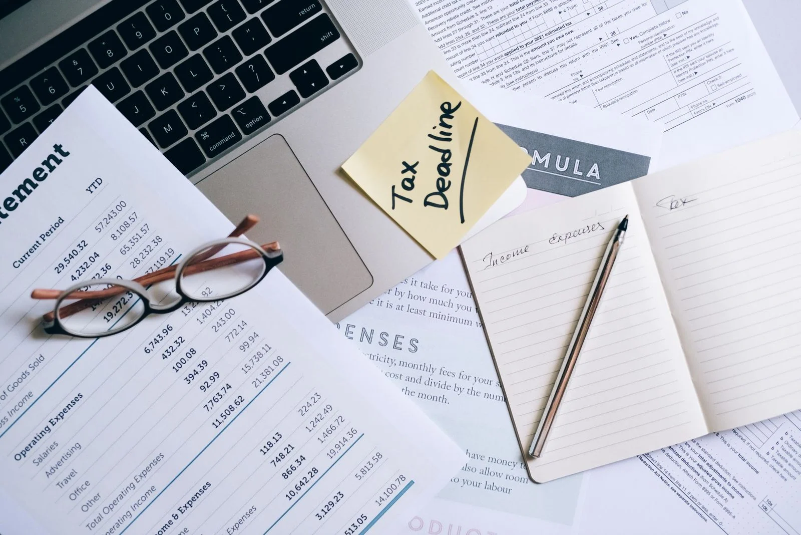 Laptop, documents, and a handwritten tax deadline note on a desk, representing financial management for a special needs trust.
