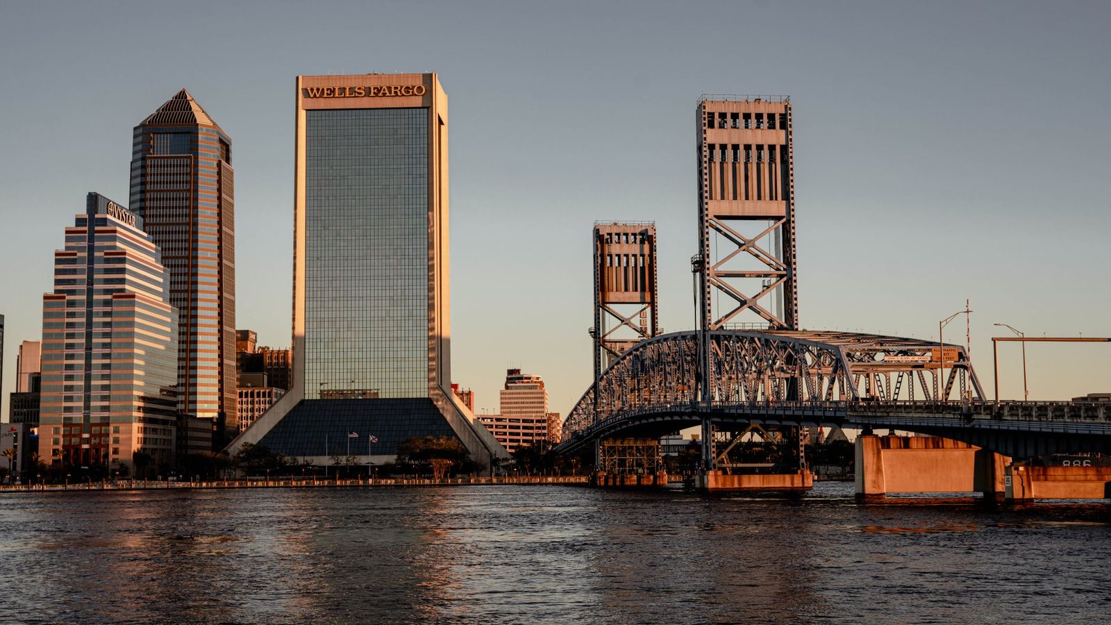 Jacksonville, Florida skyline at sunset, with skyscrapers and bridges reflected on the river.