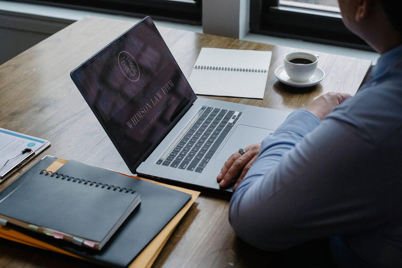Overhead view of an unidentified businessman working on a netbook beside documents and a cup of hot coffee.