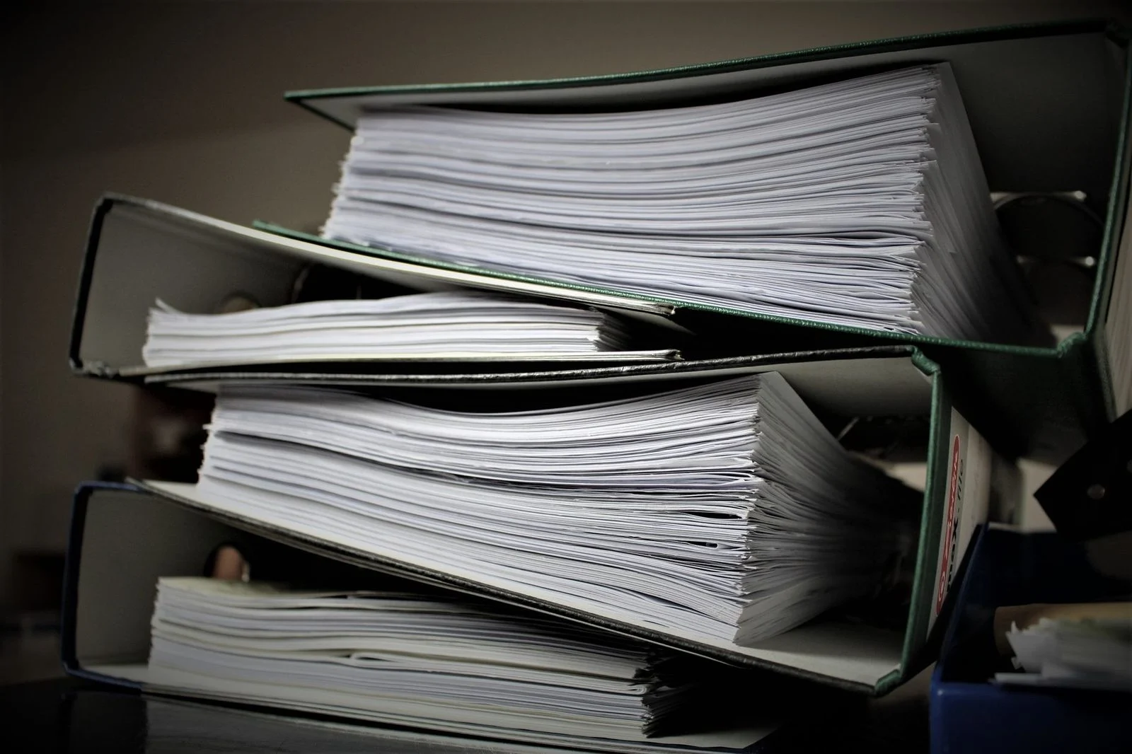 Stacked binders filled with documents on a desk.