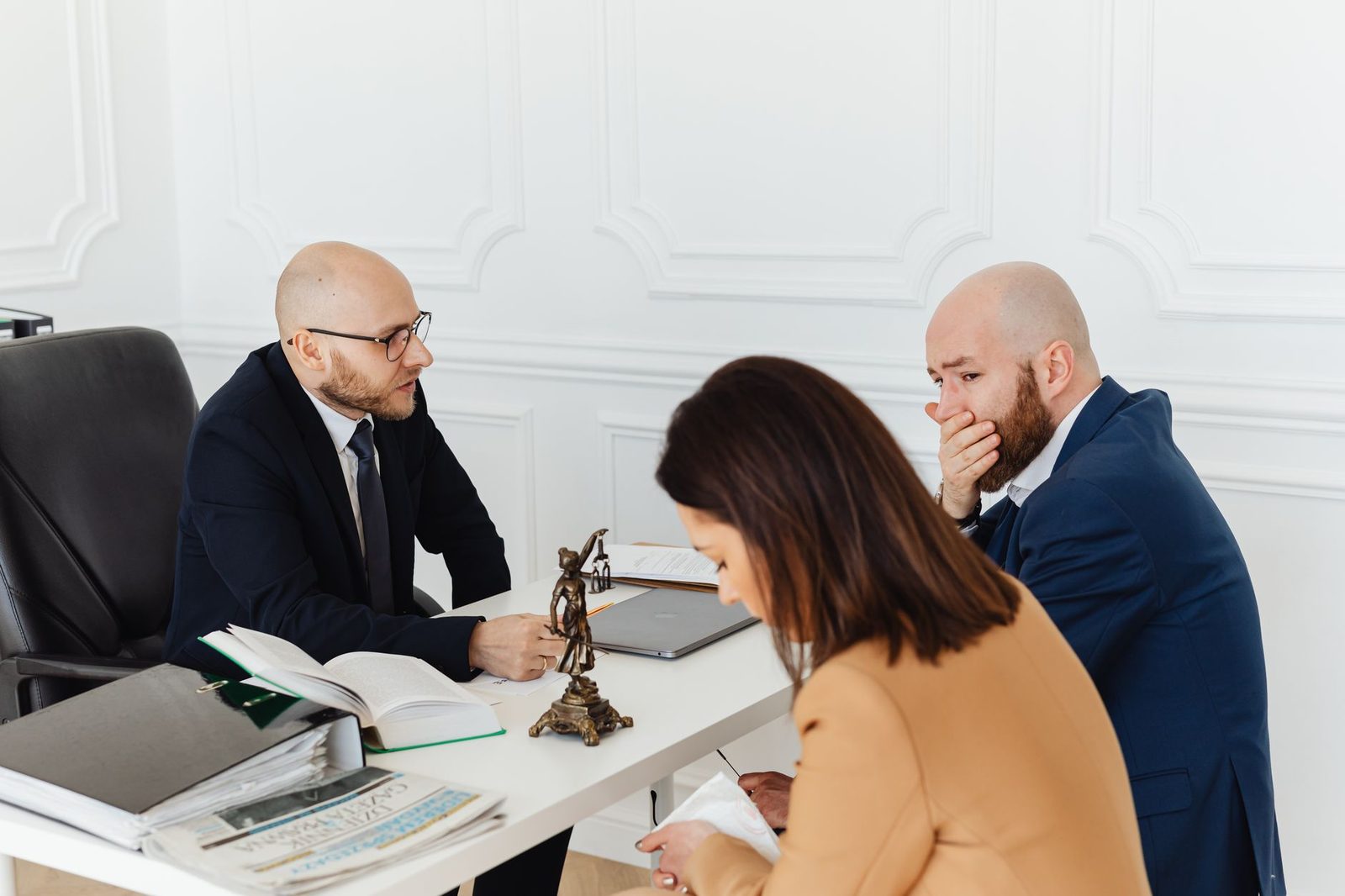 Three adults meet in a professional office for a serious legal consultation with a trust litigation attorney.