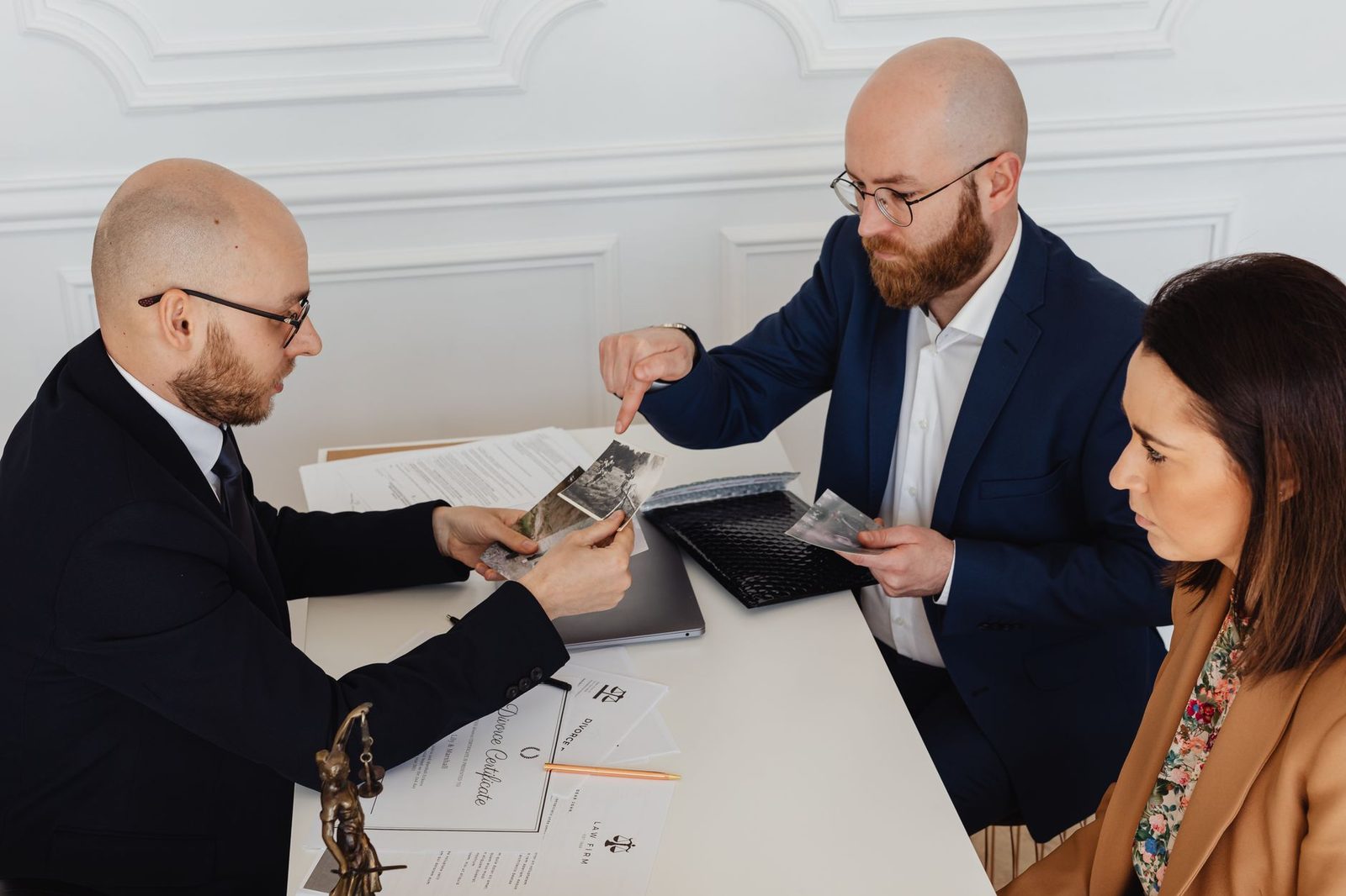 Dos abogados se reúnen con un cliente en una mesa de conferencias para revisar documentos de una herencia.