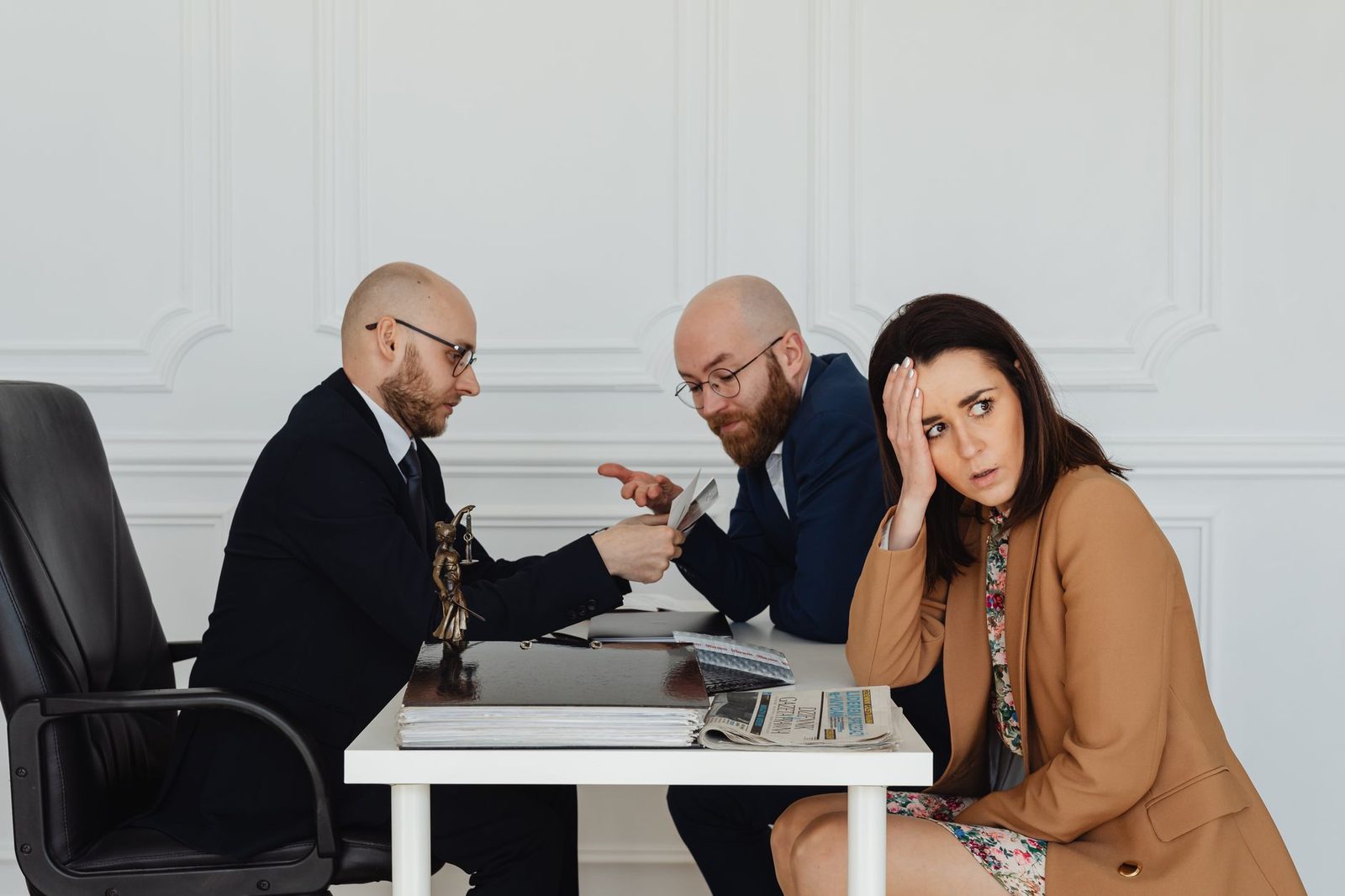 Two lawyers review documents with a concerned client across a desk in a professional office.