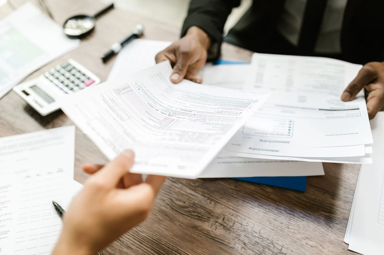 Two professionals in an office review documents together, with a focus on paperwork and data.