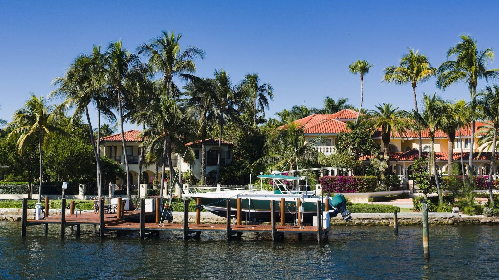 Waterfront homes with palm trees and a docked boat along a Fort Lauderdale, Florida canal.