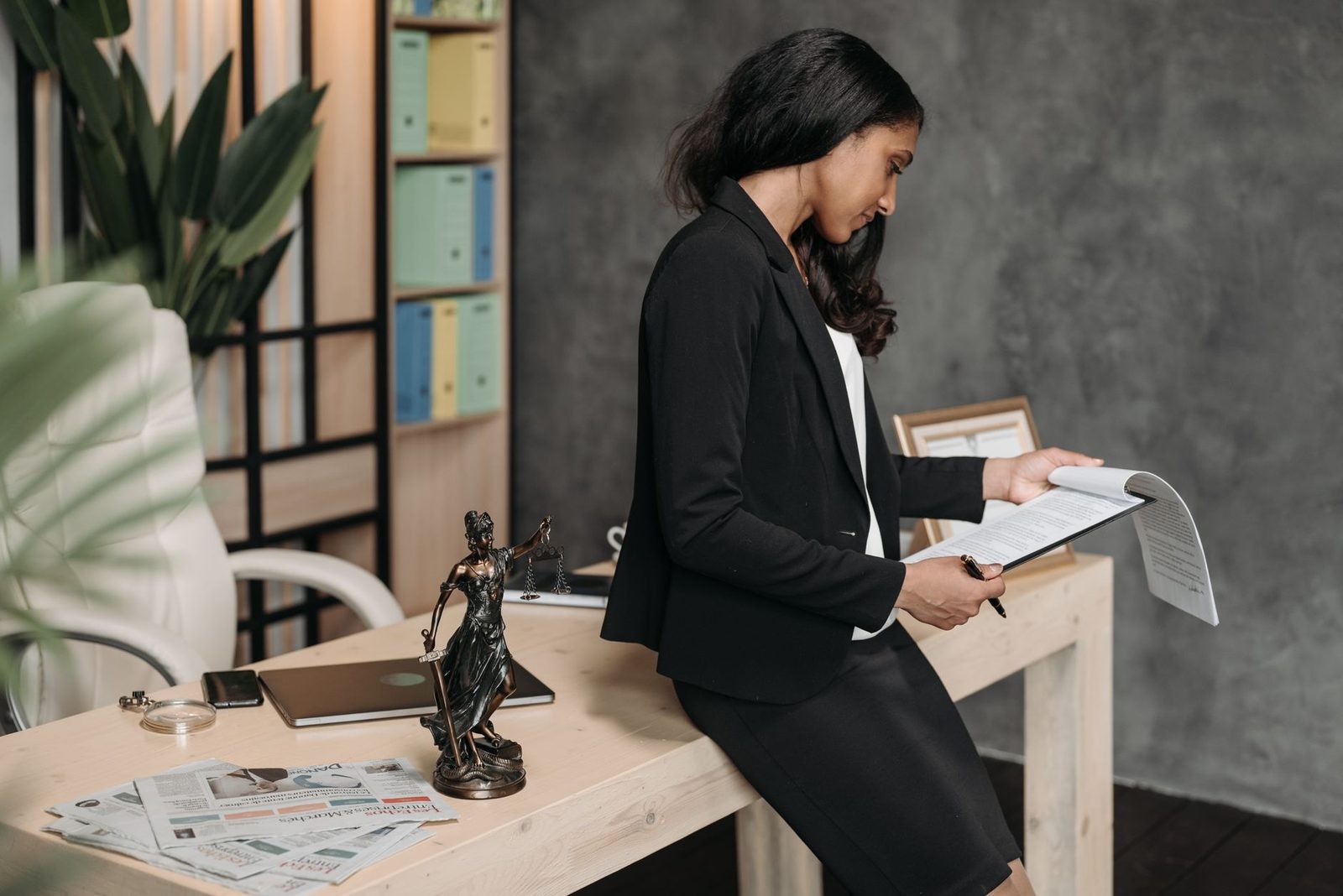 Woman in business suit reviewing legal documents at office desk.