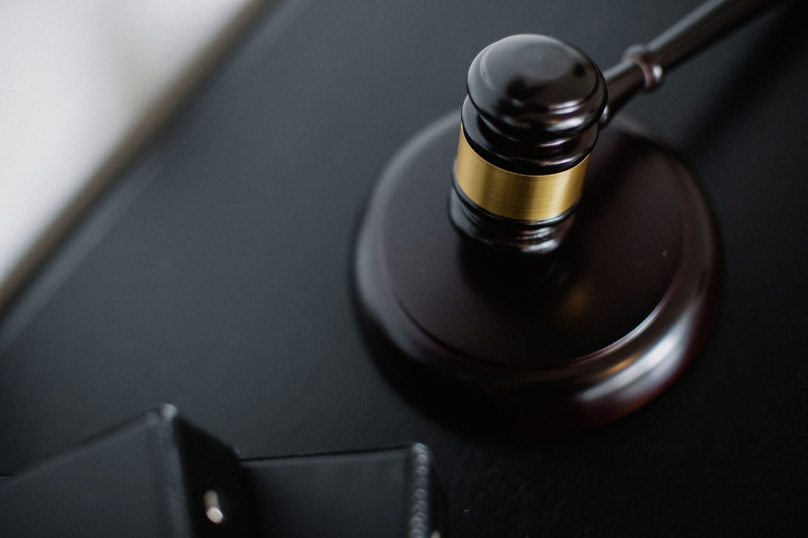 Wooden gavel resting on a round surface beside folders on a courtroom table.