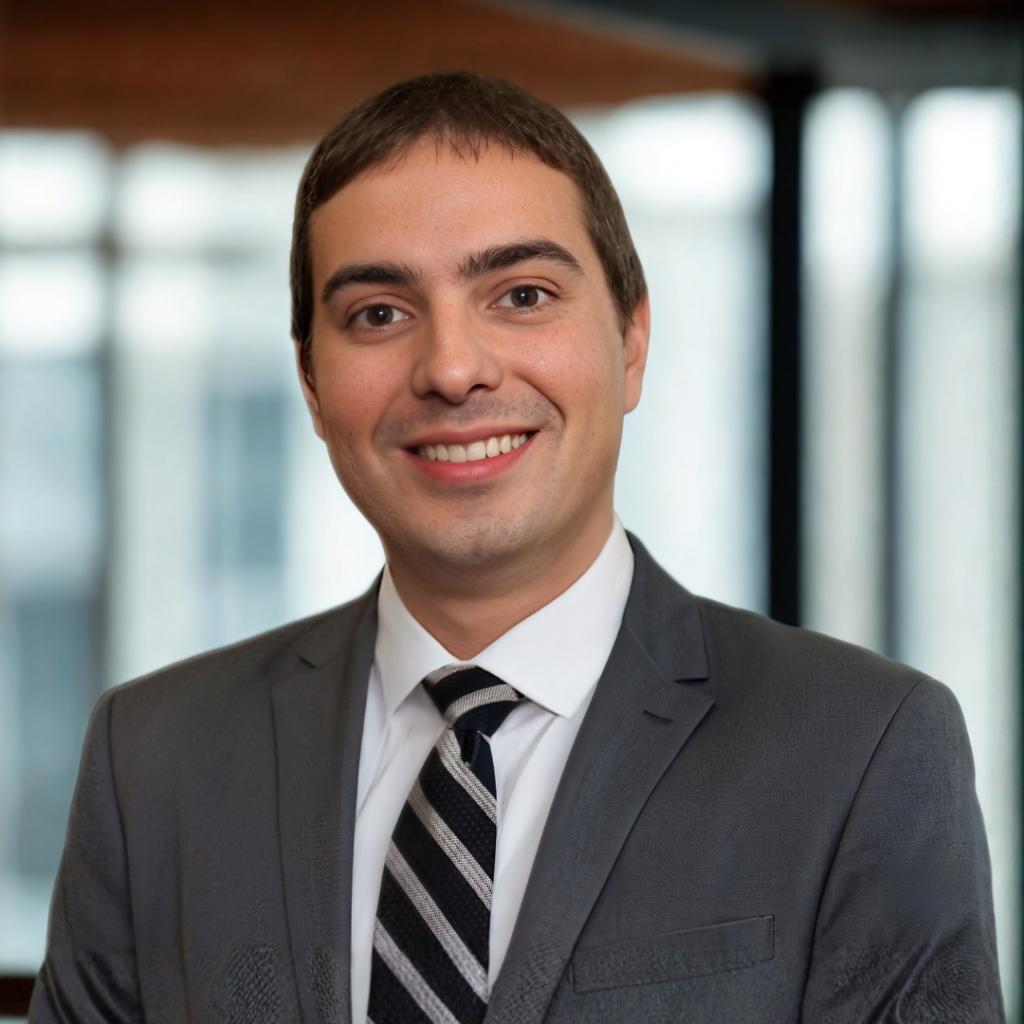 Professional portrait of a man in a gray suit and striped tie smiling at the camera, indoors in soft light.