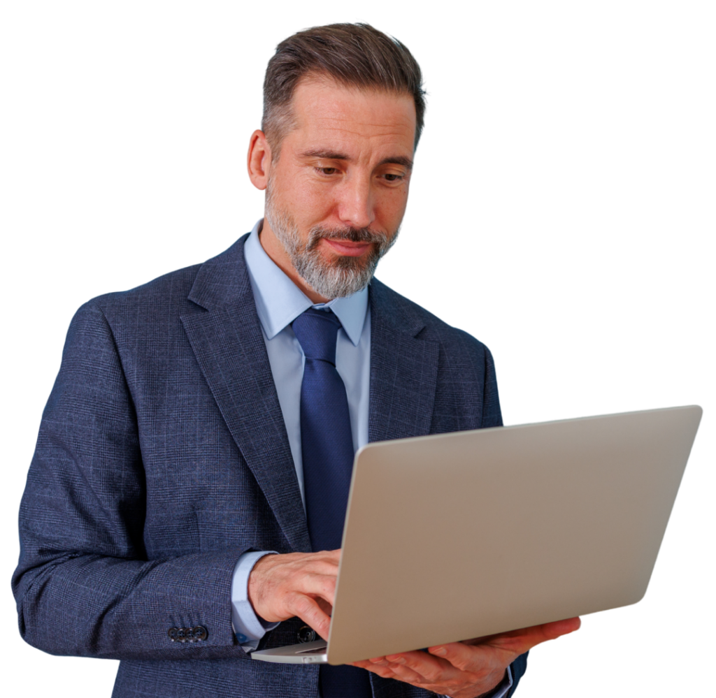 Businessman in a navy suit and blue tie typing on a silver laptop, focused on his work.