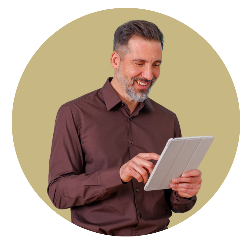 Man with short gray hair and beard, wearing a brown shirt, smiling while using a tablet.
