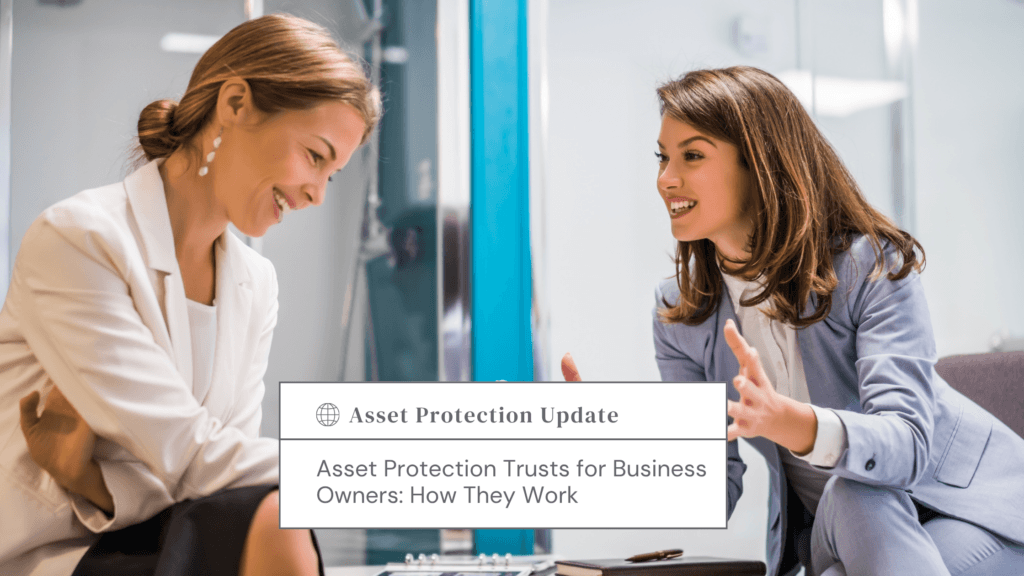 Two women in business attire smile and discuss a document titled Asset Protection Update on a desk in a bright office.