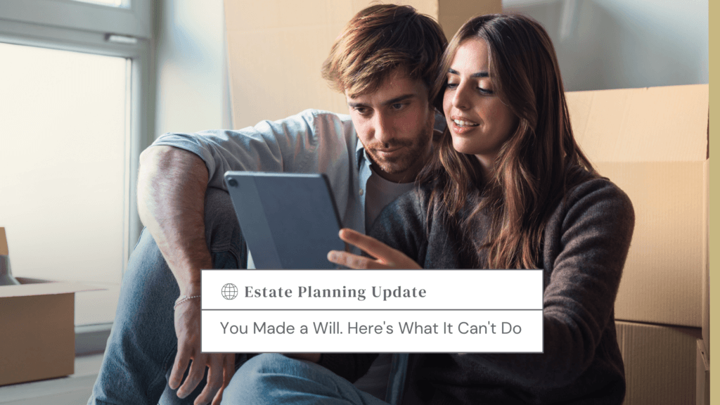Couple sits among moving boxes, looking at a tablet together in a bright room.